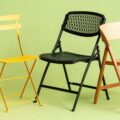 Folding fishing chair set up on a grassy lake shore beside a rod